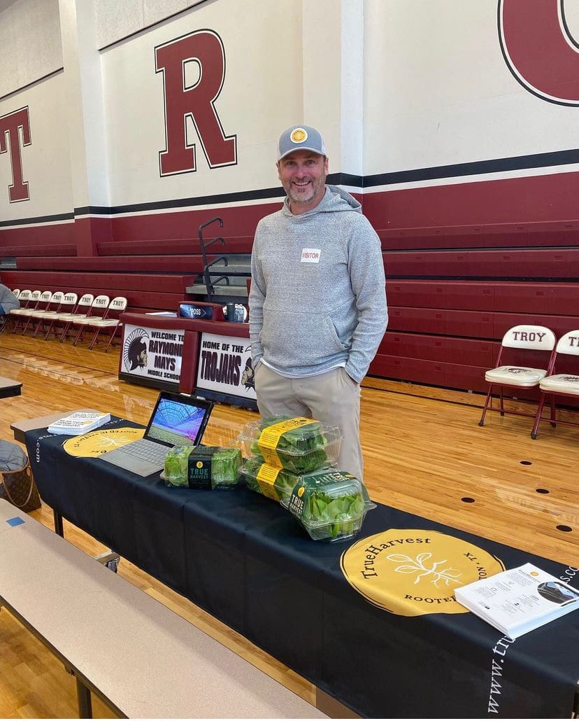 Man standing in front of a promotional table smiling.