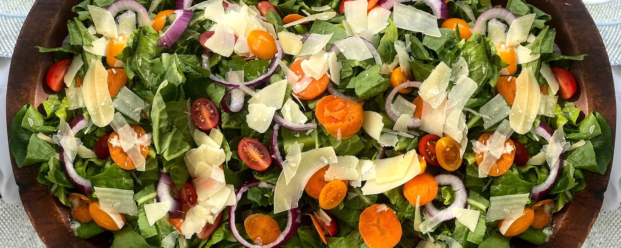 TrueHarvest Italian salad with carrots, tomatoes, onion and cheese in a wooden salad bowl.